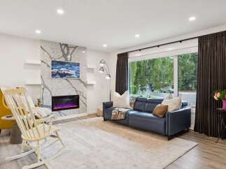 Experience modern living in this stunning living room, featuring a sleek electric fireplace set against a dramatic stone accent wall.