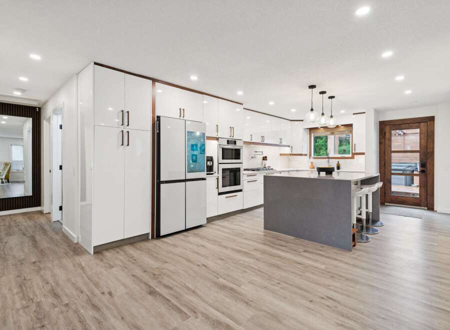 Experience modern living in this stunning kitchen featuring sleek white cabinetry with rich wood accents and a large grey island perfect for entertaining.