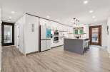 Experience modern living in this stunning kitchen featuring sleek white cabinetry with rich wood accents and a large grey island perfect for entertaining.