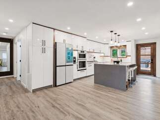 Experience modern living in this stunning kitchen featuring sleek white cabinetry with rich wood accents and a large grey island perfect for entertaining.