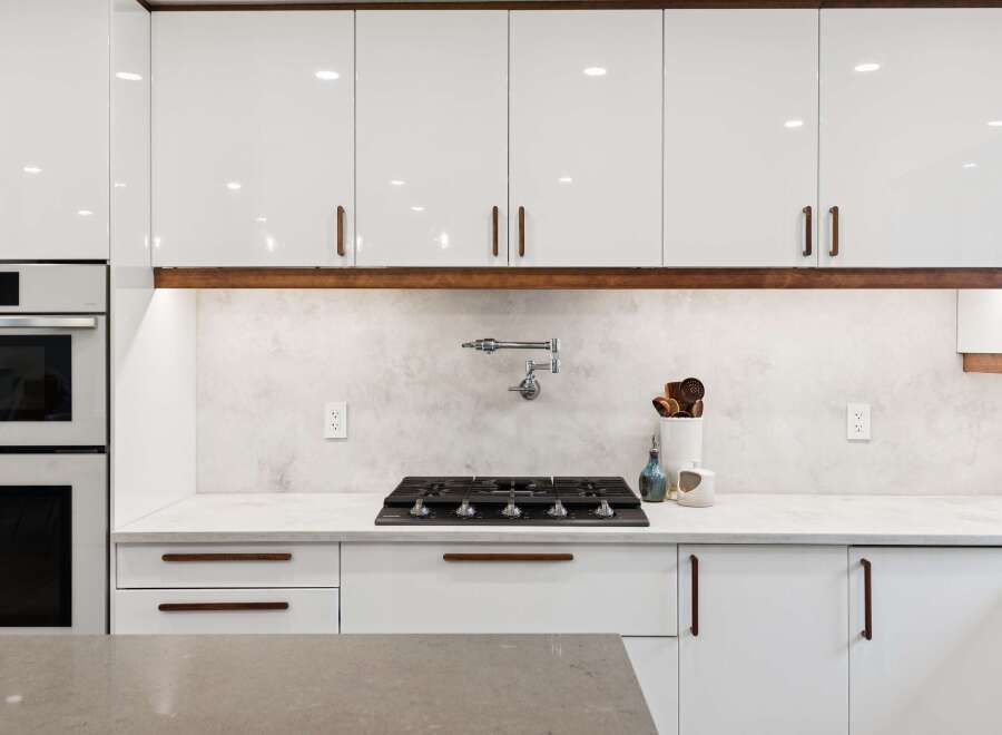 Experience modern luxury in this stunning kitchen, featuring sleek white cabinetry with elegant wood accents.