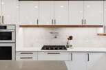Experience modern luxury in this stunning kitchen, featuring sleek white cabinetry with elegant wood accents.