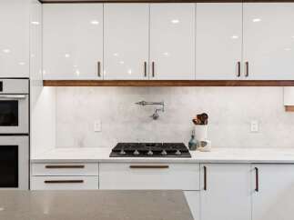 Experience modern luxury in this stunning kitchen, featuring sleek white cabinetry with elegant wood accents.