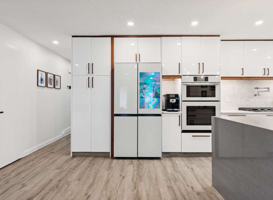 Experience modern luxury in this stunning kitchen, featuring sleek white cabinetry and a state-of-the-art smart refrigerator.