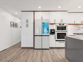 Experience modern luxury in this stunning kitchen, featuring sleek white cabinetry and a state-of-the-art smart refrigerator.