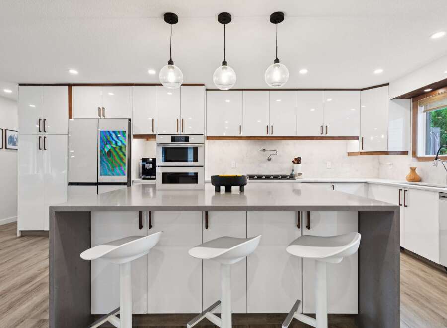 Experience modern luxury in this stunning kitchen, featuring sleek white cabinetry with warm wood accents and a spacious quartz island perfect for entertaining.