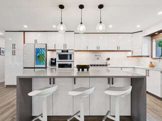 Experience modern luxury in this stunning kitchen, featuring sleek white cabinetry with warm wood accents and a spacious quartz island perfect for entertaining.