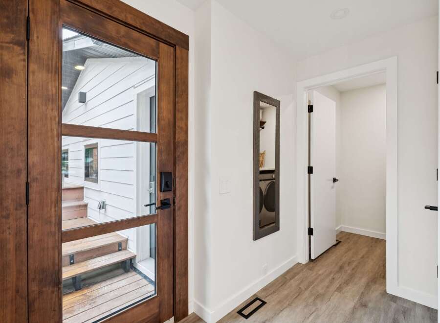Step into this inviting entryway featuring a stunning wooden door with glass panels, offering a glimpse of the exterior.