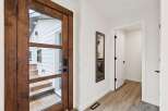 Step into this inviting entryway featuring a stunning wooden door with glass panels, offering a glimpse of the exterior.
