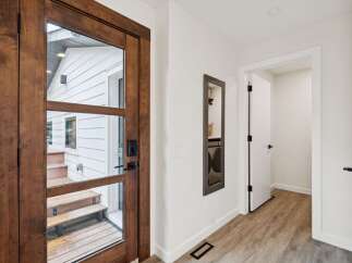 Step into this inviting entryway featuring a stunning wooden door with glass panels, offering a glimpse of the exterior.