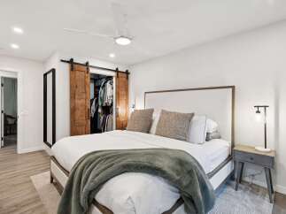 Experience ultimate comfort in this master bedroom, featuring a plush king-sized bed adorned with a cozy green throw blanket.