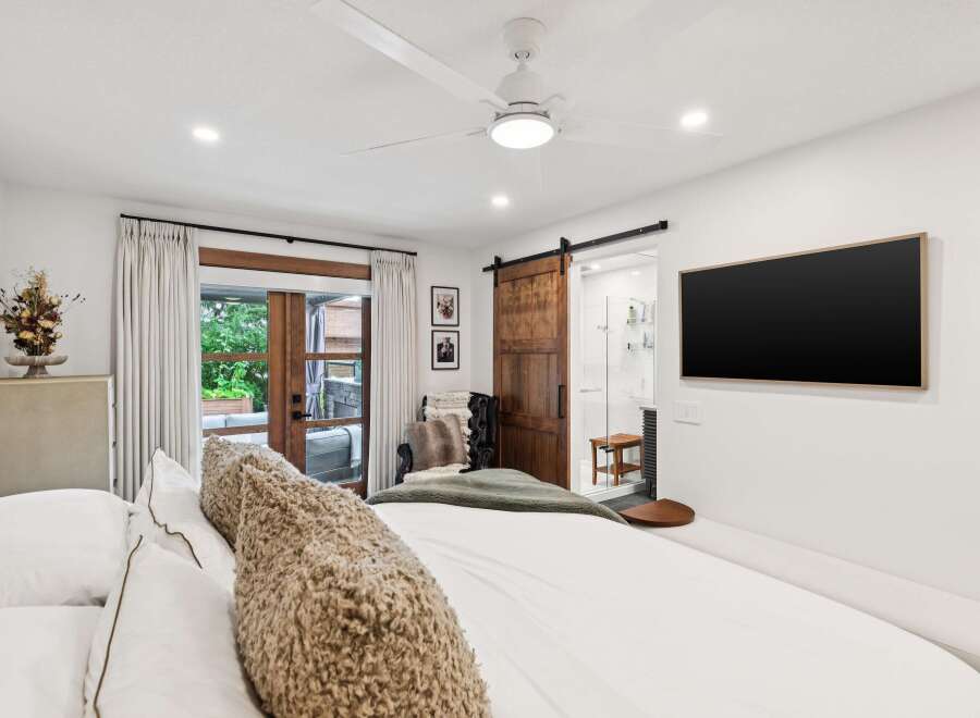Experience modern luxury in this master suite featuring a king-sized bed with plush bedding and a cozy textured throw.