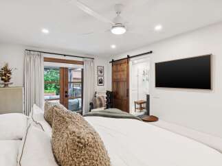 Experience modern luxury in this master suite featuring a king-sized bed with plush bedding and a cozy textured throw.
