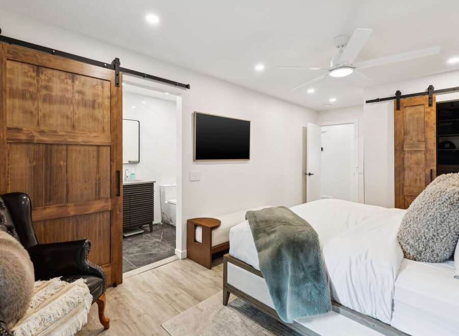 Experience modern luxury in this master bedroom featuring a sleek barn door leading to an en-suite bathroom.