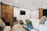 Experience modern luxury in this master bedroom featuring a sleek barn door leading to an en-suite bathroom.