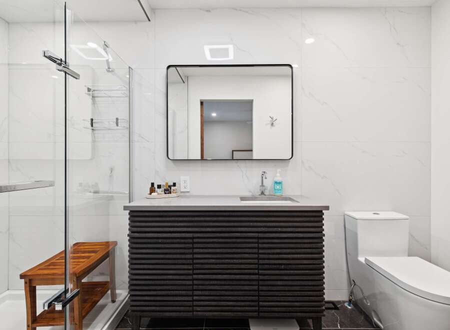 Experience modern luxury in this stunning bathroom featuring a sleek vanity with ample storage and a minimalist aesthetic.