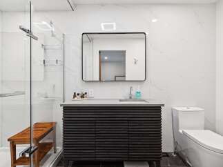 Experience modern luxury in this stunning bathroom featuring a sleek vanity with ample storage and a minimalist aesthetic.