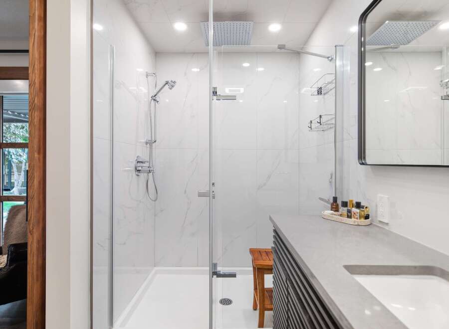 Experience luxury in this modern bathroom featuring a spacious walk-in shower with marble-look tiles and a rainfall showerhead.