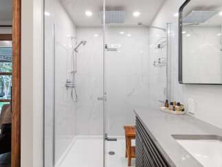 Experience luxury in this modern bathroom featuring a spacious walk-in shower with marble-look tiles and a rainfall showerhead.