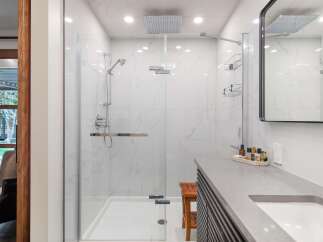 Experience luxury in this modern bathroom featuring a spacious walk-in shower with marble-look tiles and a rainfall showerhead.