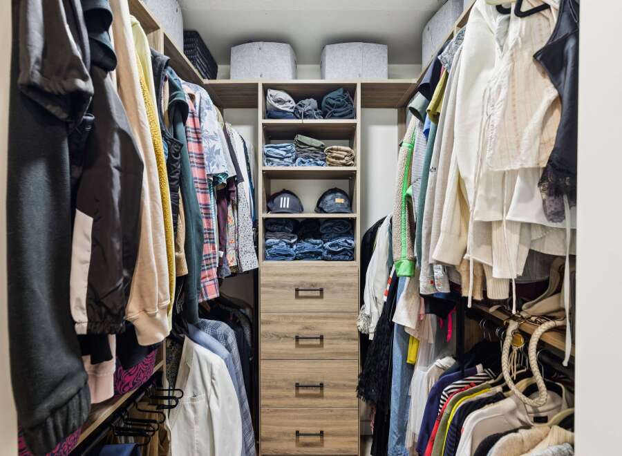 Discover organized living with this spacious walk-in closet, featuring ample hanging space and neatly stacked shelves for clothing and accessories.