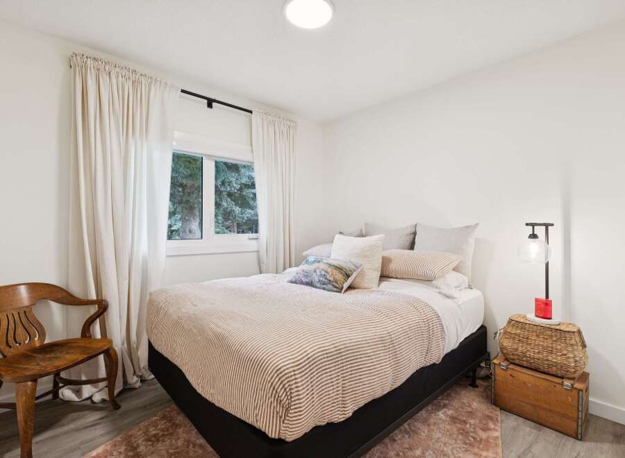 Experience serene comfort in this inviting bedroom, featuring a plush bed adorned with striped linens and an array of cozy pillows.