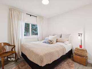 Experience serene comfort in this inviting bedroom, featuring a plush bed adorned with striped linens and an array of cozy pillows.