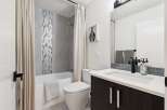 This modern bathroom features a sleek vanity with a white countertop and dark wood cabinetry, complemented by a stylish black faucet.