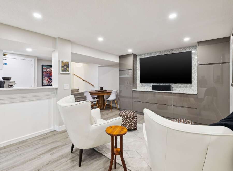 This modern living space features a large flat-screen TV mounted above sleek, grey cabinetry, perfect for entertainment.