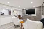 This modern living space features a large flat-screen TV mounted above sleek, grey cabinetry, perfect for entertainment.