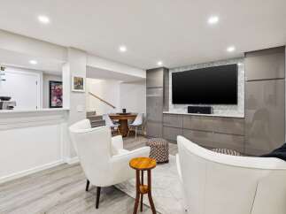This modern living space features a large flat-screen TV mounted above sleek, grey cabinetry, perfect for entertainment.