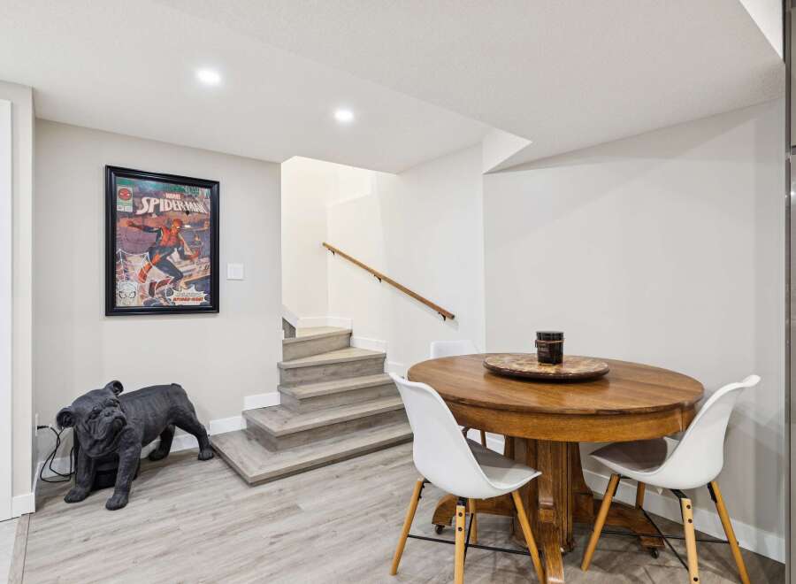 Discover this charming basement space featuring a stylish dining area with a round wooden table and white chairs, perfect for intimate gatherings.