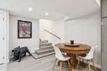 Discover this charming basement space featuring a stylish dining area with a round wooden table and white chairs, perfect for intimate gatherings.