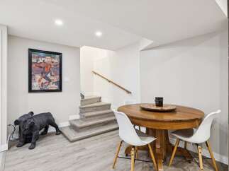 Discover this charming basement space featuring a stylish dining area with a round wooden table and white chairs, perfect for intimate gatherings.