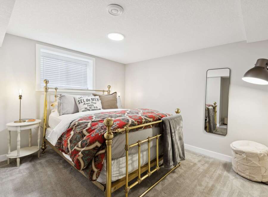 Experience comfort and style in this charming bedroom, featuring a beautiful brass bed frame adorned with a vibrant, patterned duvet.