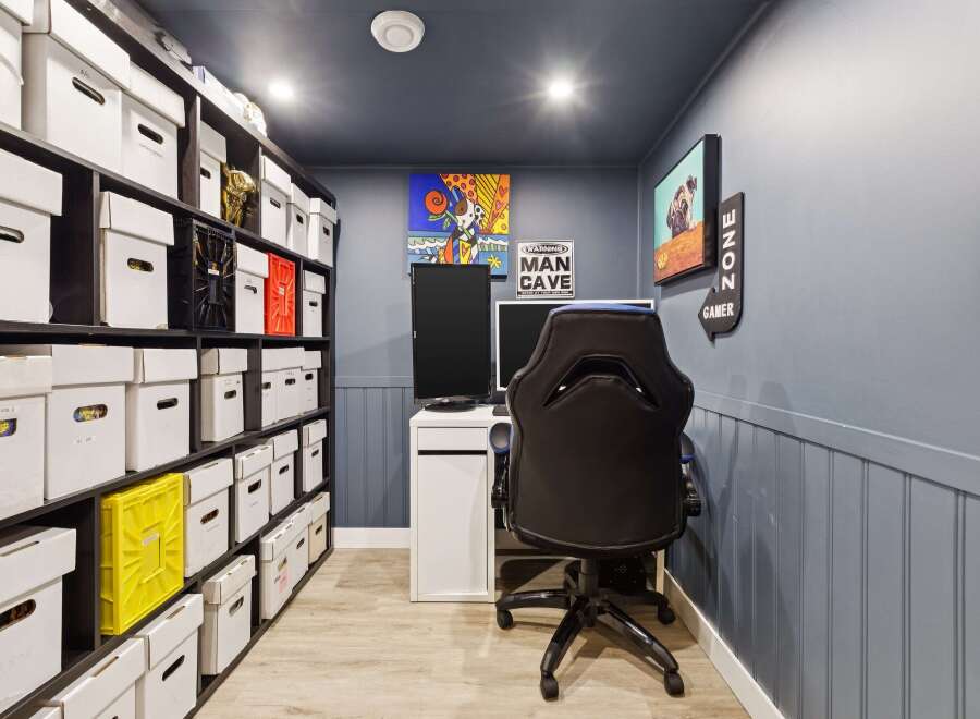 Discover your ultimate sanctuary in this dedicated gaming room, featuring ample storage for your collectibles and a comfortable gaming setup.