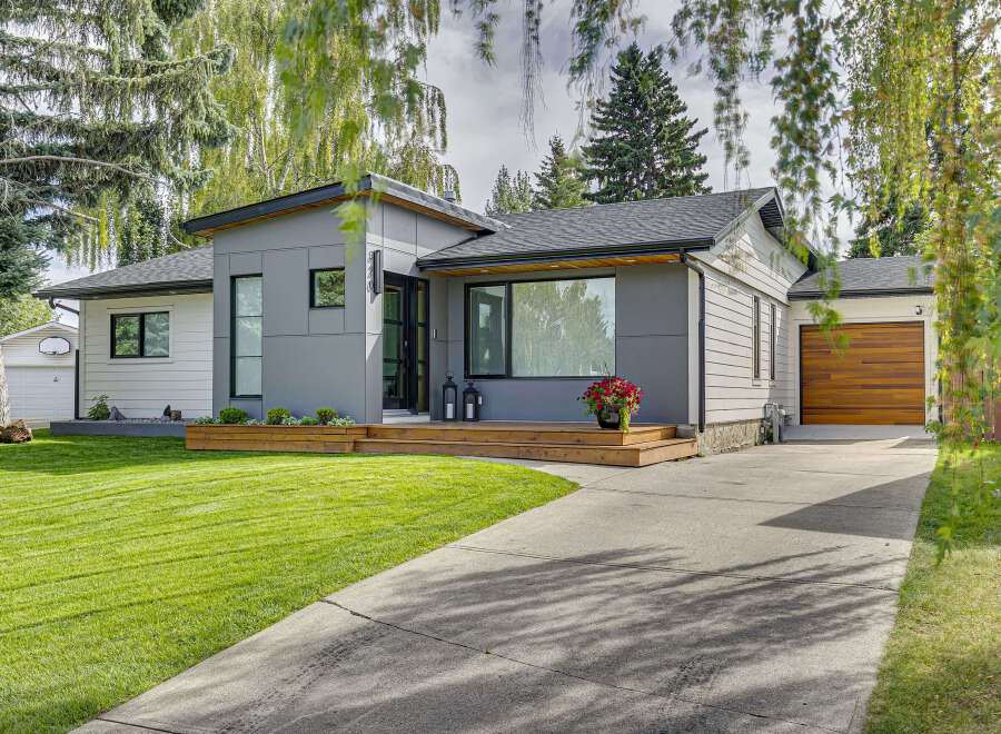 Discover modern living in this beautifully renovated home featuring a sleek grey exterior with wood accents and a welcoming front porch.