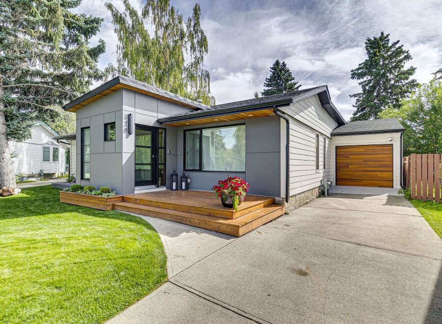 Discover modern living in this beautifully renovated home featuring a sleek grey exterior and a welcoming wooden deck.