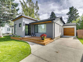 Discover modern living in this beautifully renovated home featuring a sleek grey exterior and a welcoming wooden deck.