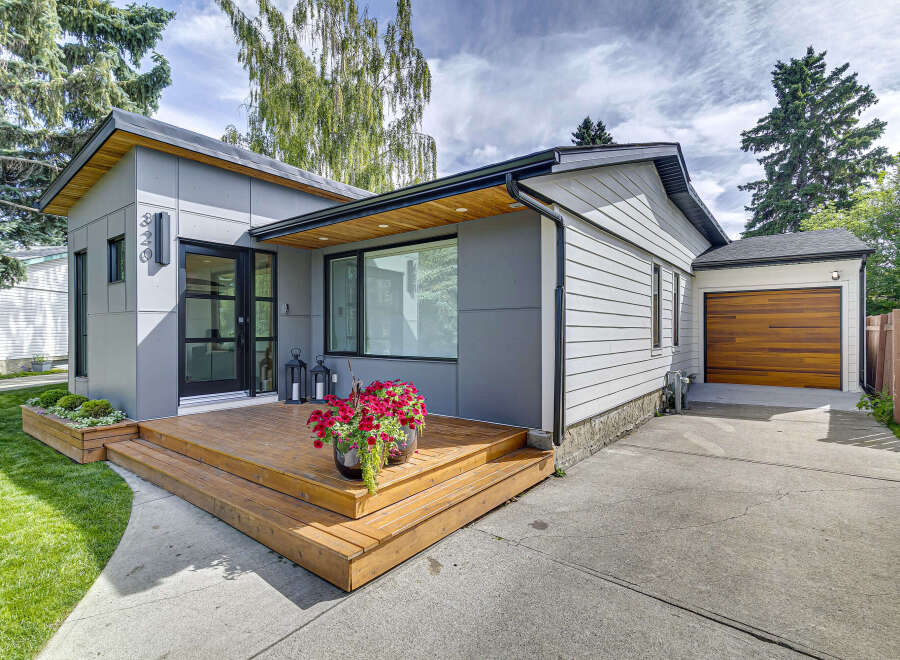 Discover modern living in this stunning home featuring a sleek grey exterior and a welcoming wooden deck.