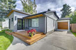 Discover modern living in this stunning home featuring a sleek grey exterior and a welcoming wooden deck.