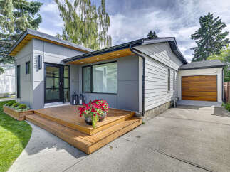 Discover modern living in this stunning home featuring a sleek grey exterior and a welcoming wooden deck.