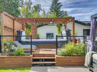 Experience ultimate relaxation in this backyard oasis, featuring a luxurious hot tub nestled on a spacious wooden deck.