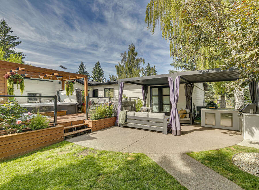 Experience ultimate outdoor living with this stunning backyard oasis, featuring a luxurious hot tub on a private wooden deck and a sleek, modern pergola providing shade over a comfortable seating area.