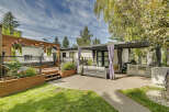 Experience ultimate outdoor living with this stunning backyard oasis, featuring a luxurious hot tub on a private wooden deck and a sleek, modern pergola providing shade over a comfortable seating area.