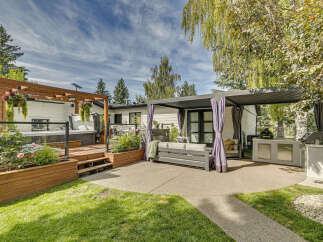 Experience ultimate outdoor living with this stunning backyard oasis, featuring a luxurious hot tub on a private wooden deck and a sleek, modern pergola providing shade over a comfortable seating area.