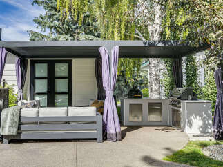 Enjoy outdoor living at its finest with this covered patio featuring a built-in outdoor kitchen and comfortable seating area.