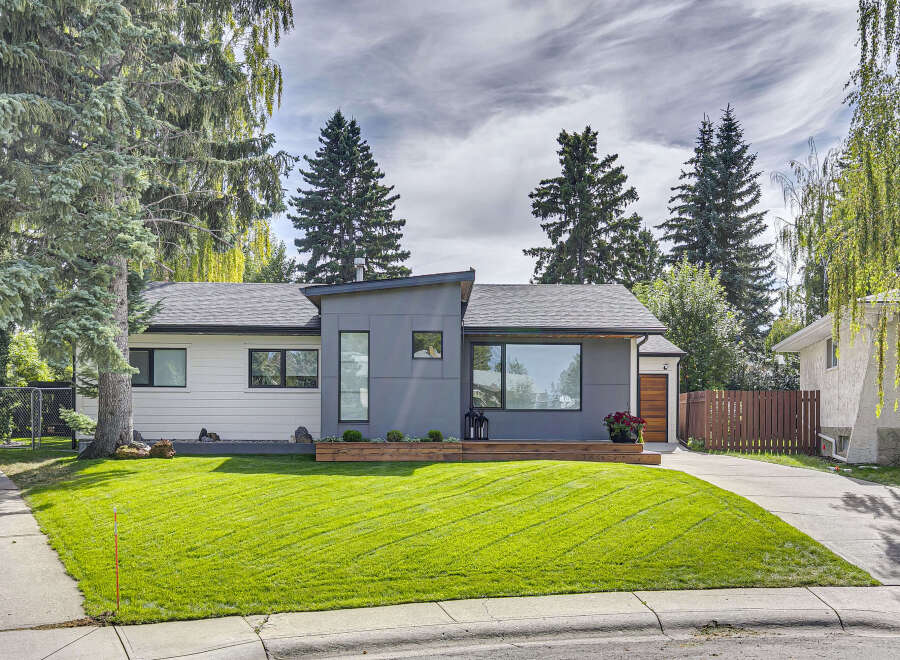 Experience modern living in this beautifully renovated home featuring a striking grey facade and crisp white siding.