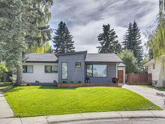 Experience modern living in this beautifully renovated home featuring a striking grey facade and crisp white siding.