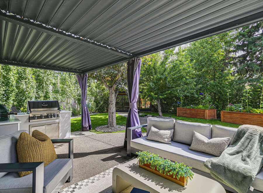 Enjoy outdoor living at its finest with this covered patio featuring a built-in grill station and comfortable seating.